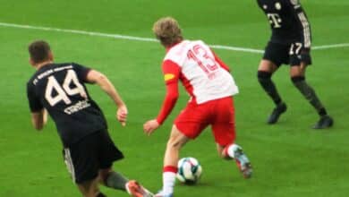 Un footballeur en maillot rouge dribble sur le terrain