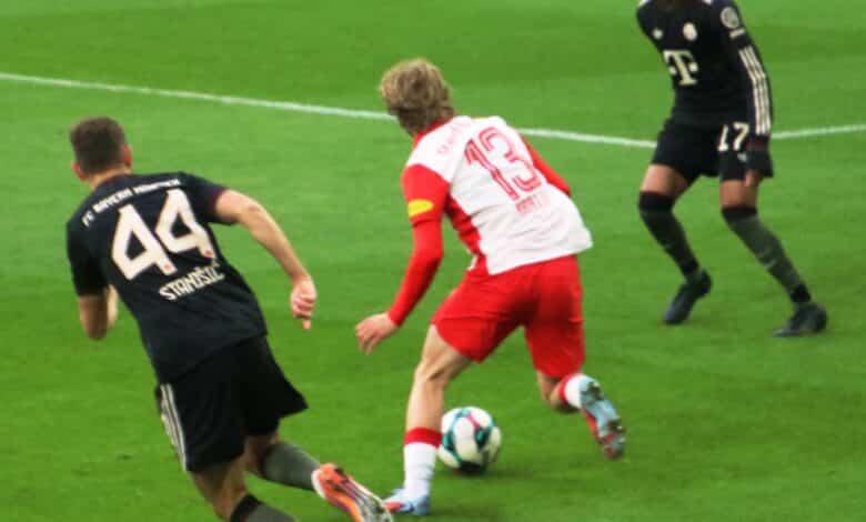 Olise peut-il prolonger sa forme de septembre ? 1 Un footballeur en maillot rouge dribble sur le terrain